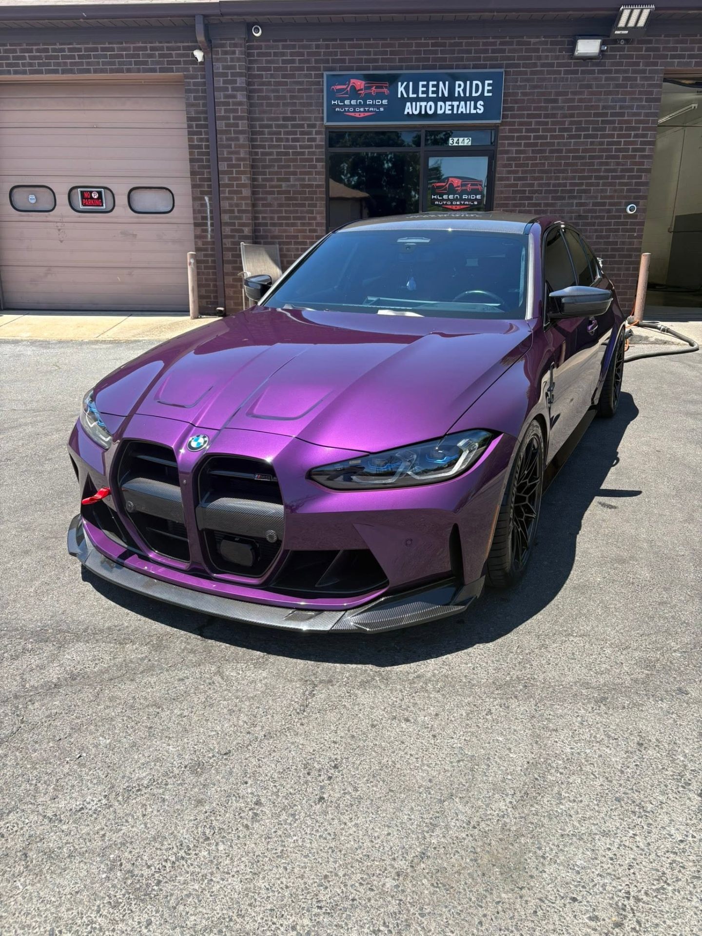 Front view of a purple BMW M3 with carbon fiber splitter after a Kleen Ride hand wash
